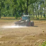 Traktor rozsypuje nawóz na polu. Wapnowanie gleby kiedy najlepiej? Jesień lub wczesna wiosna to idealny czas.