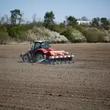 Czerwony traktor z siewnikiem precyzyjnym na polu. Rolnik dba o to, jak głęboko siać rzepak, by zapewnić mu optymalne warunki do wzrostu.